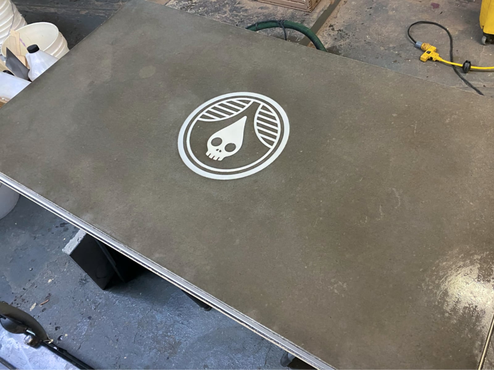 Host stand top: the Rhinegeist logo in pigmented resin, inlaid flush in poured concrete